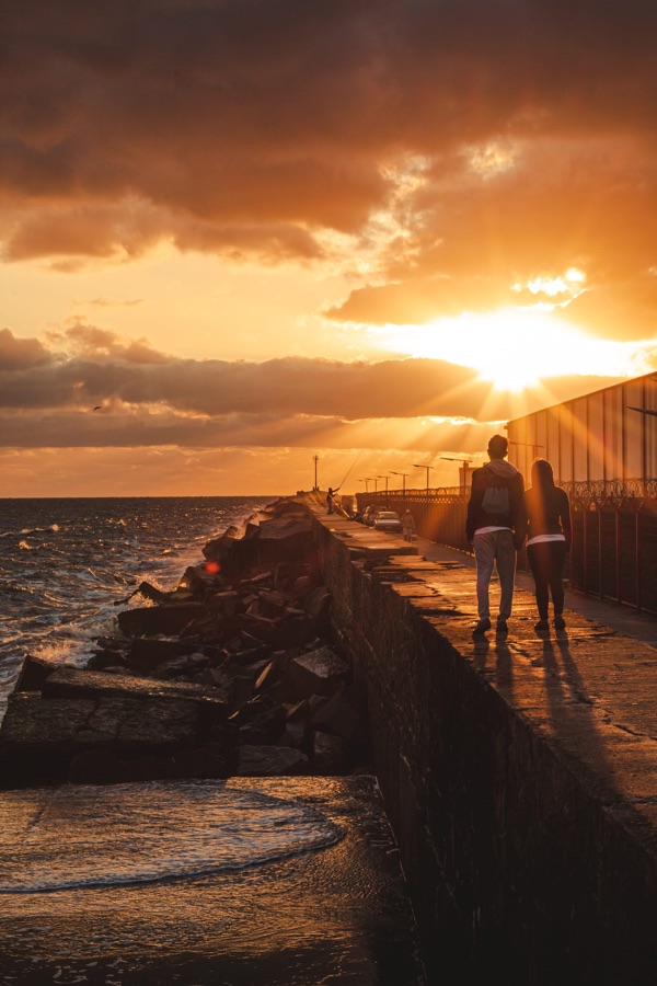 Casal caminhando no pier ao pôr do sol
